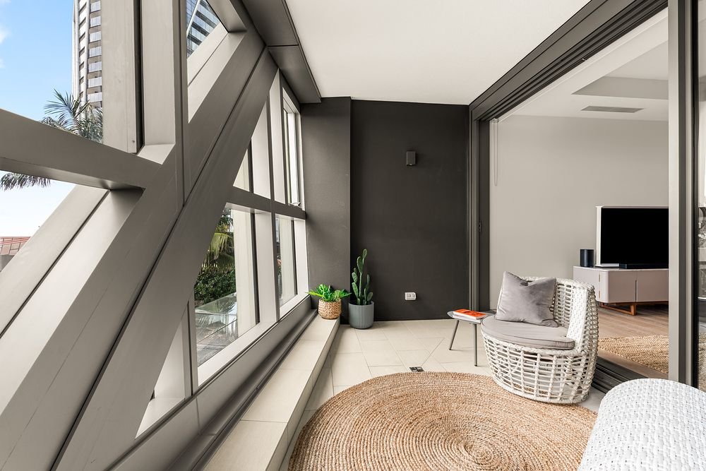 Enclosed balcony with a rattan chair and large framed windows