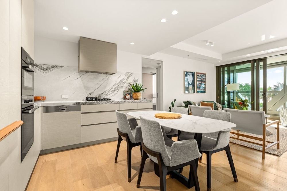 Kitchen with a marble splashback and gas cooktop, beside a round dining table for four
