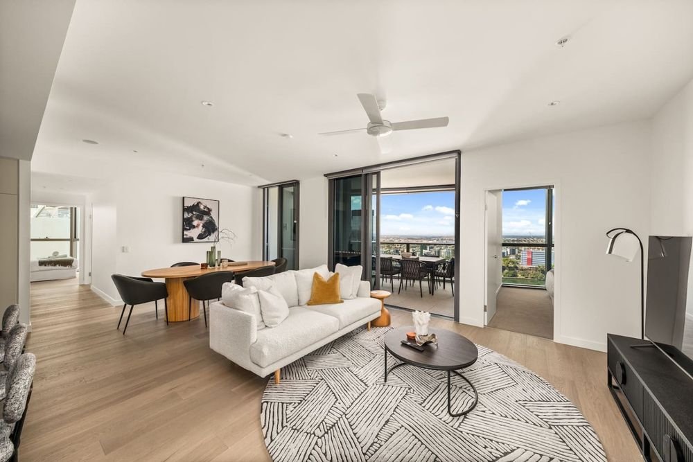 Open-plan living and dining room with a white sofa, balcony doors and a ceiling fan