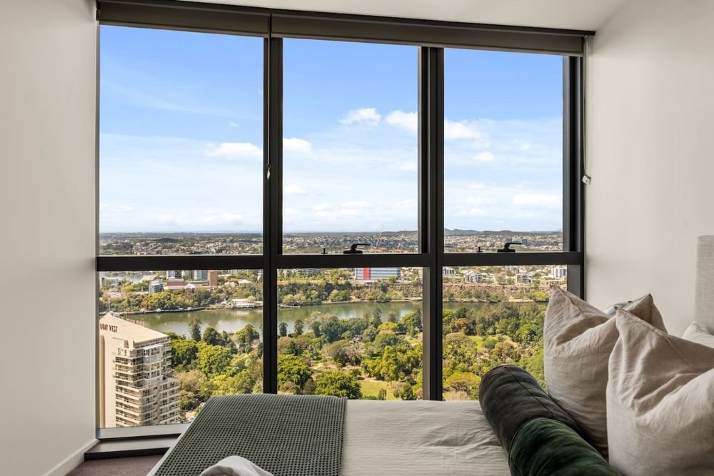 Bedroom with floor-to-ceiling windows over the river and parkland